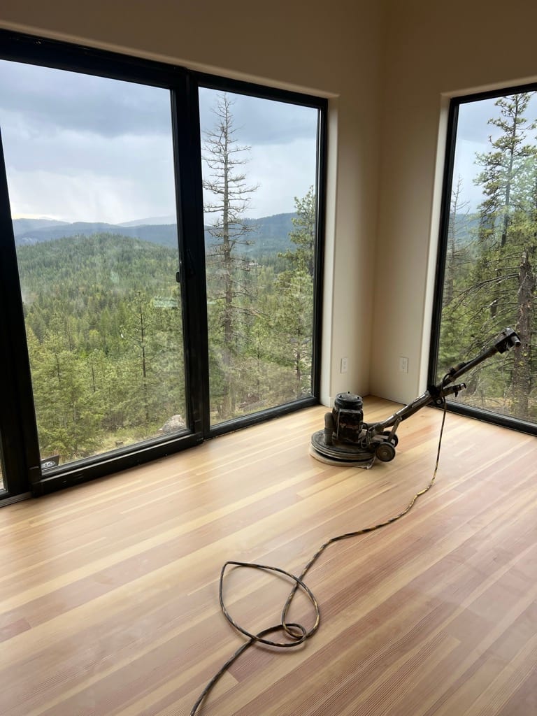 Drum sander refinishing hardwood floor with North Idaho mountain view, Rathdrum