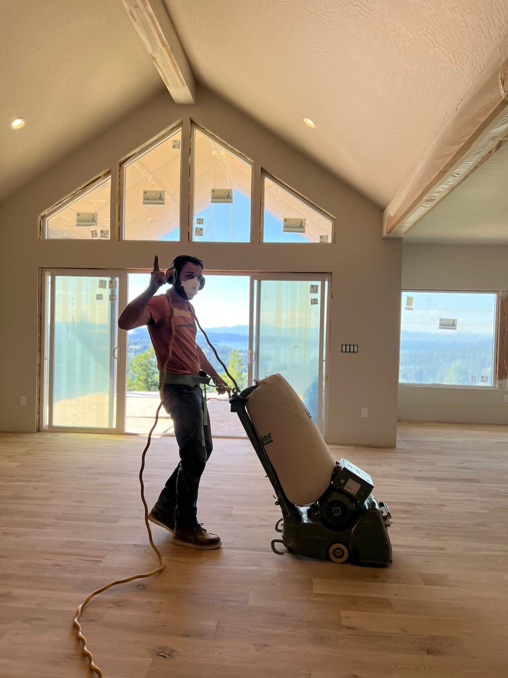 Drum sander finishing hardwood floor in vaulted-ceiling great room with mountain view, Coeur d’Alene Idaho