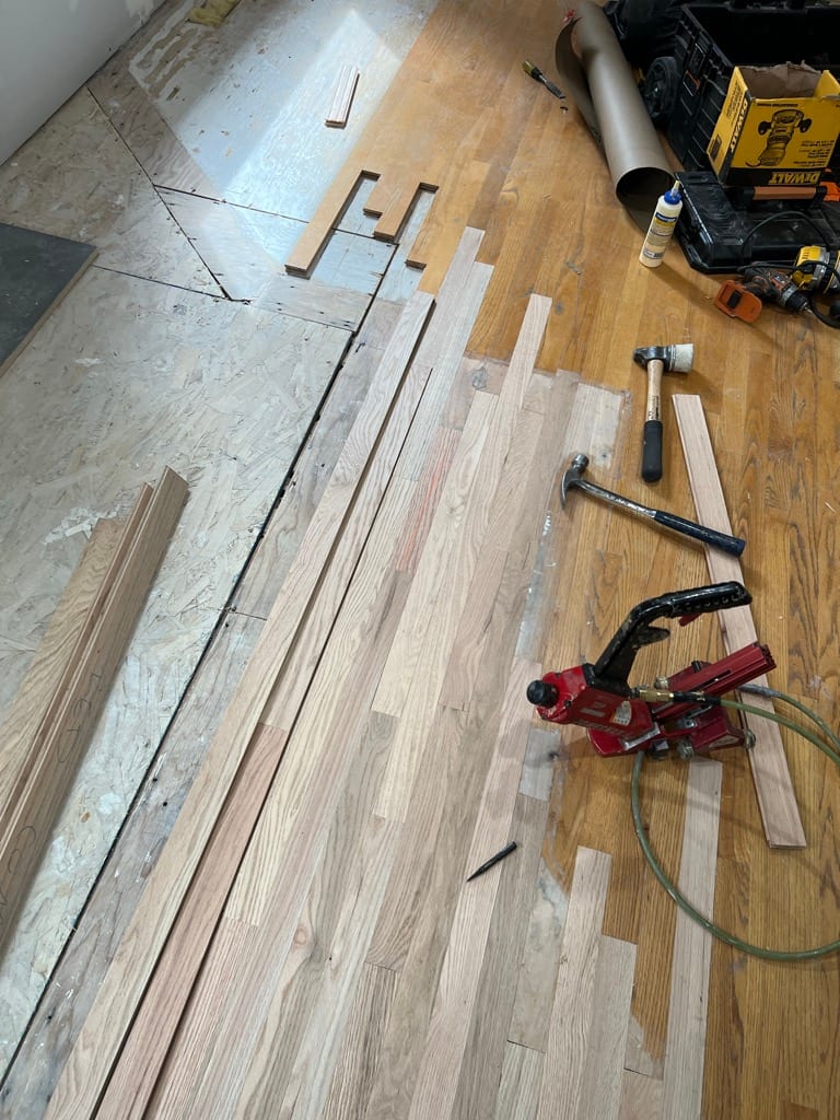 Hardwood floor repair tools laid out with fresh red oak replacement boards, Hayden Idaho