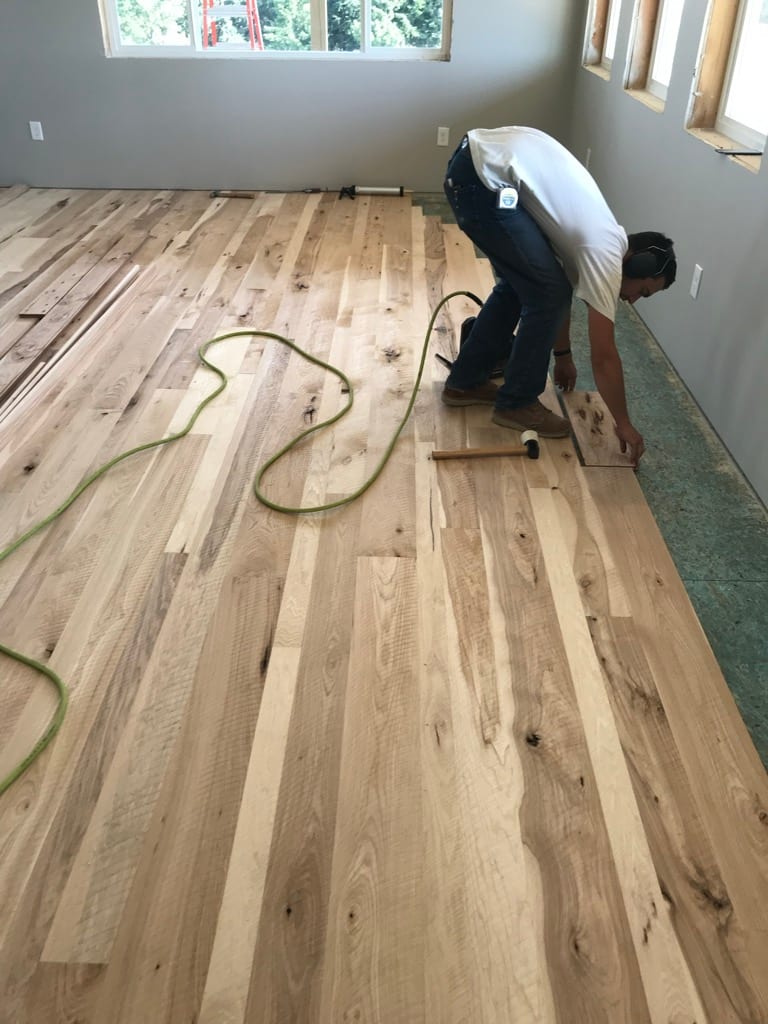 Craftsman kneeling and fitting hardwood floor boards, Post Falls Idaho