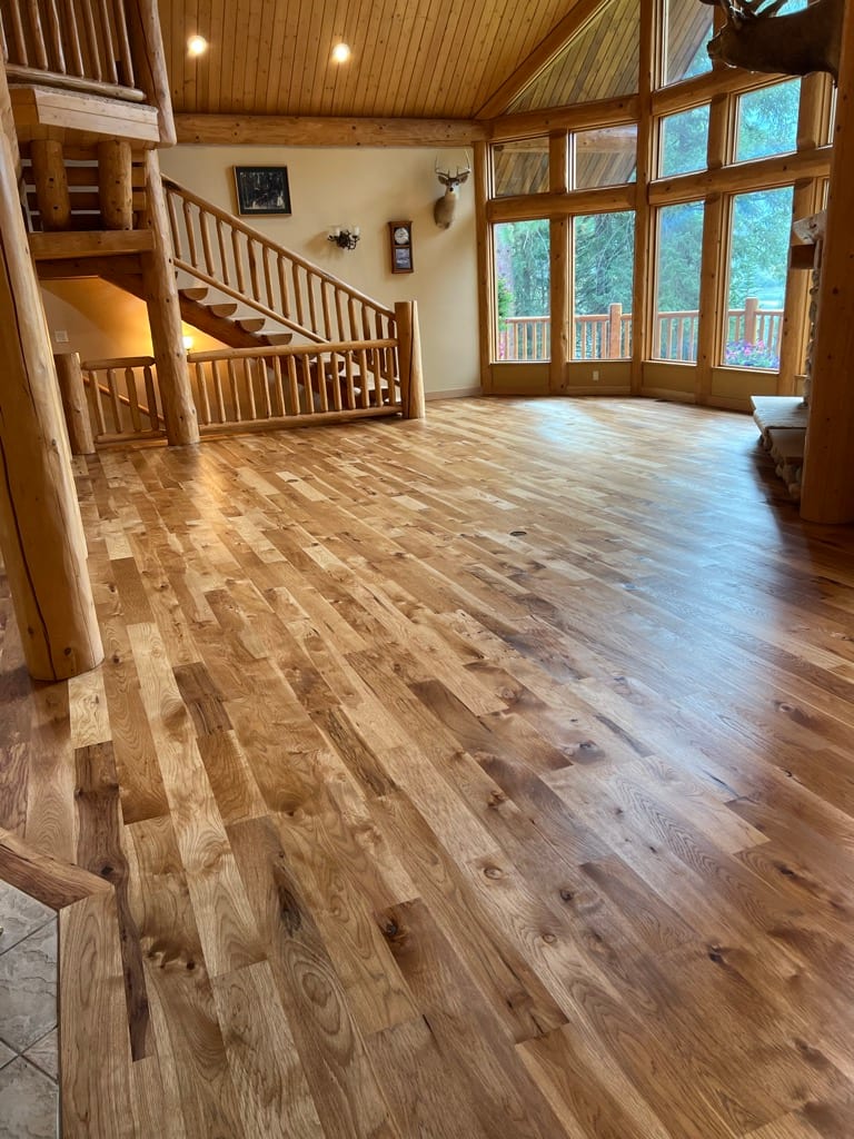 Wide-plank knotty hickory hardwood floor in vaulted log cabin, North Idaho